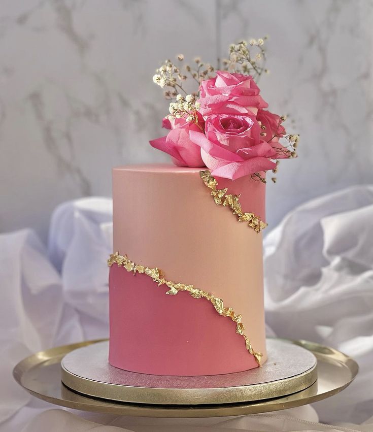 a pink and gold cake with flowers on top