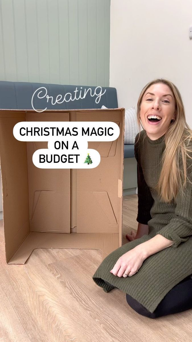 a woman sitting on the floor in front of a cardboard box with christmas magic on it