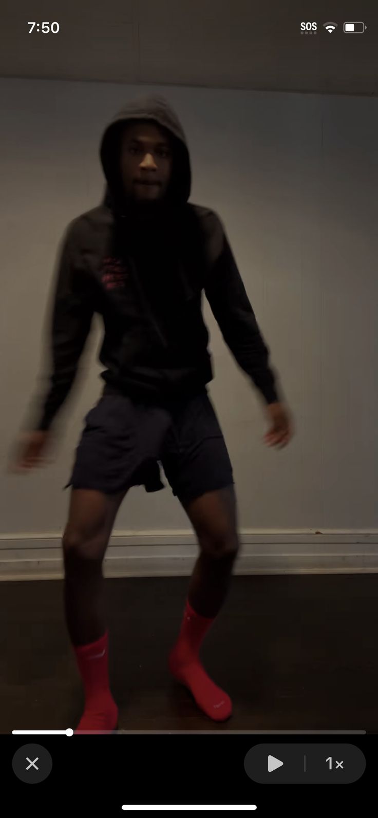 a man wearing red socks and a hoodie is dancing in front of a white wall