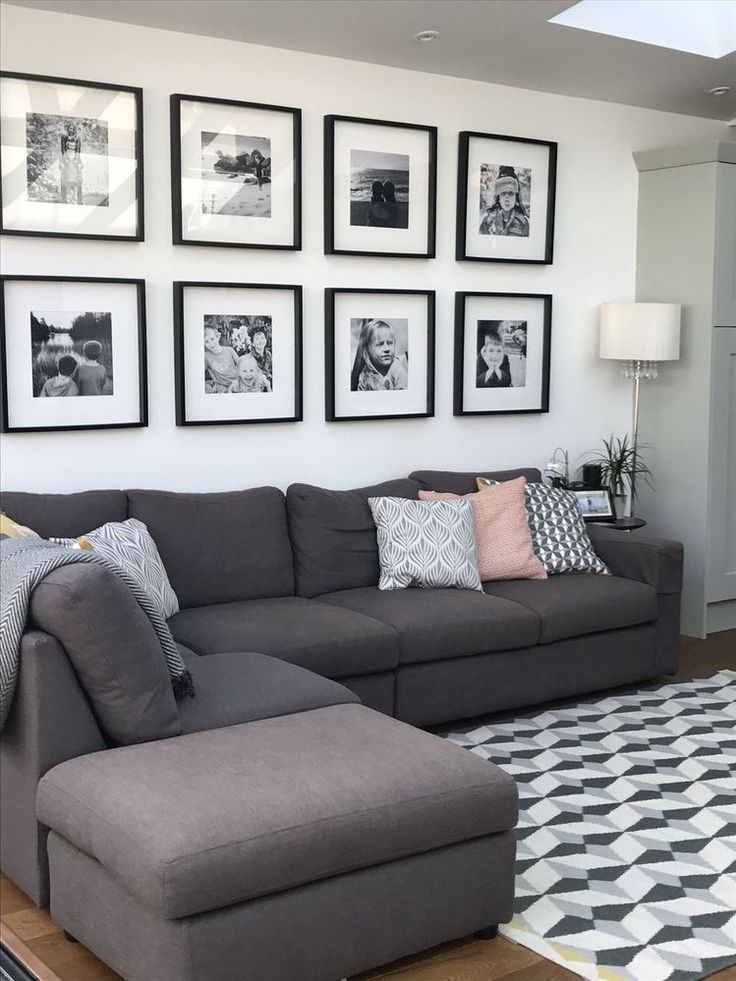 a living room with gray couches and pictures on the wall above it's coffee table