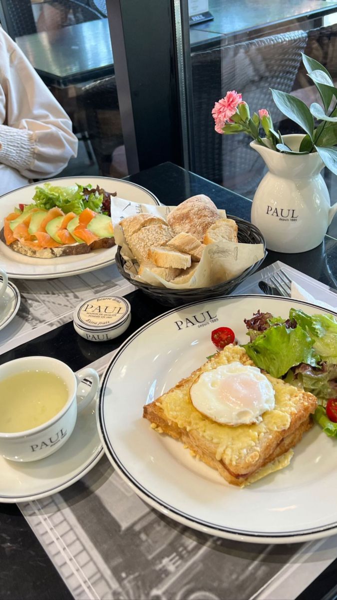 a table topped with plates of food and cups of tea next to each other on top of a glass table