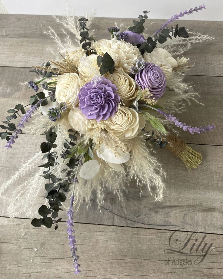 a bridal bouquet with purple flowers and greenery sits on a wooden table, ready to be used as a centerpiece