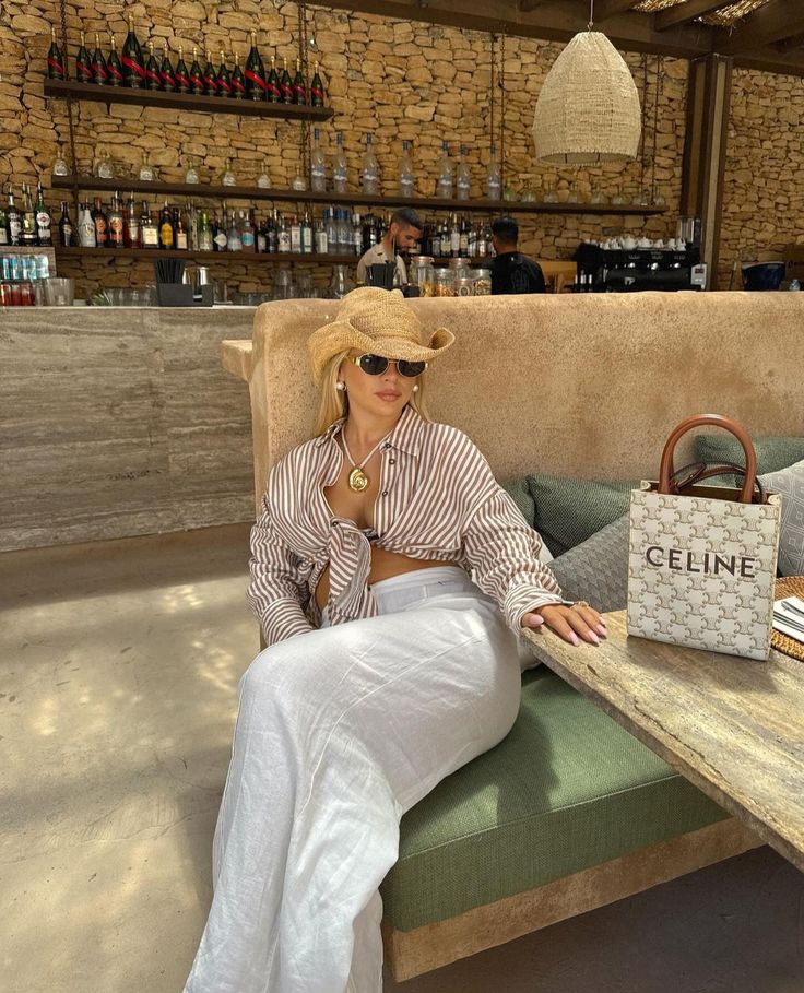 a woman sitting on a bench in front of a table with a handbag and purse