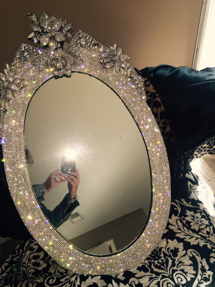 a person taking a selfie in front of a round mirror with lights on it