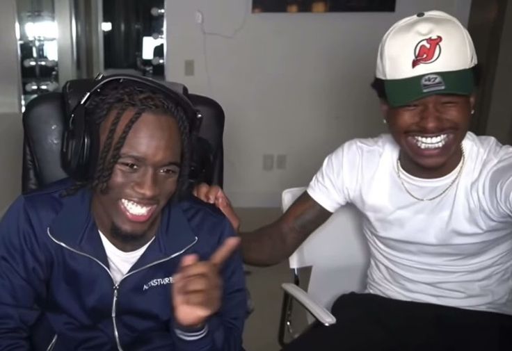 two young men sitting next to each other in front of a tv screen with headphones on