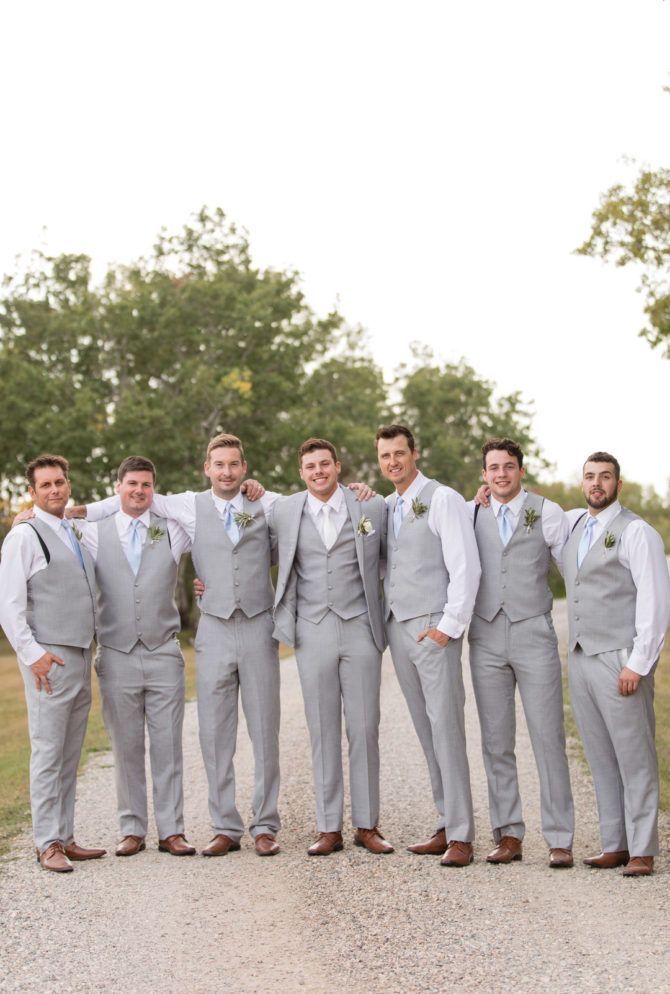 a group of men standing next to each other in front of a field and trees