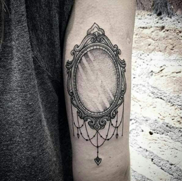 a woman's arm with a mirror tattoo on the left side of her arm