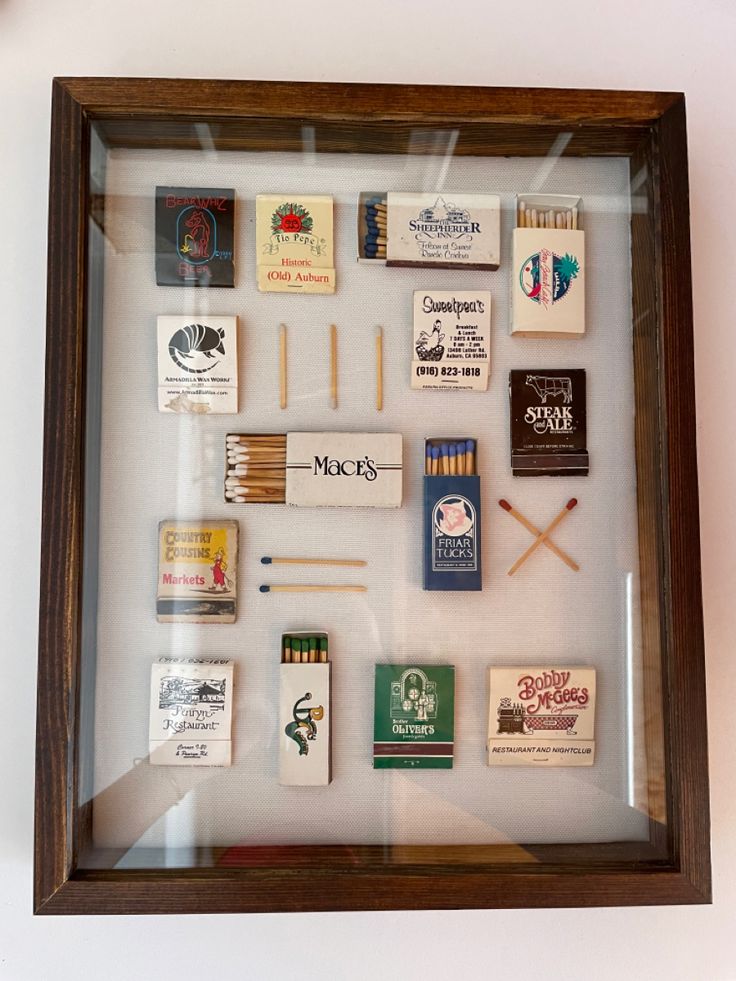 a shadow box filled with matches and matchsticks on top of a white wall