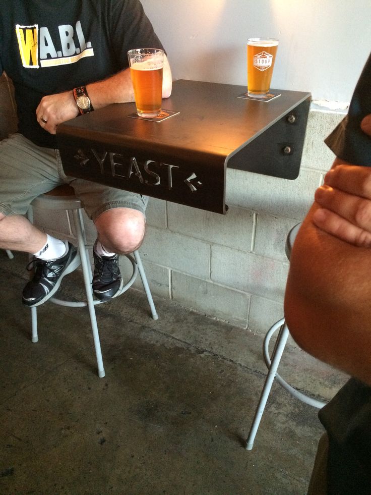 two men sitting at a table with beers in front of them