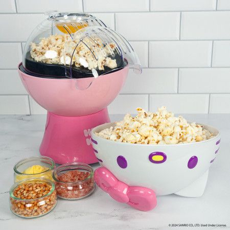 a pink and white bowl filled with popcorn next to other bowls full of popcorn on a counter