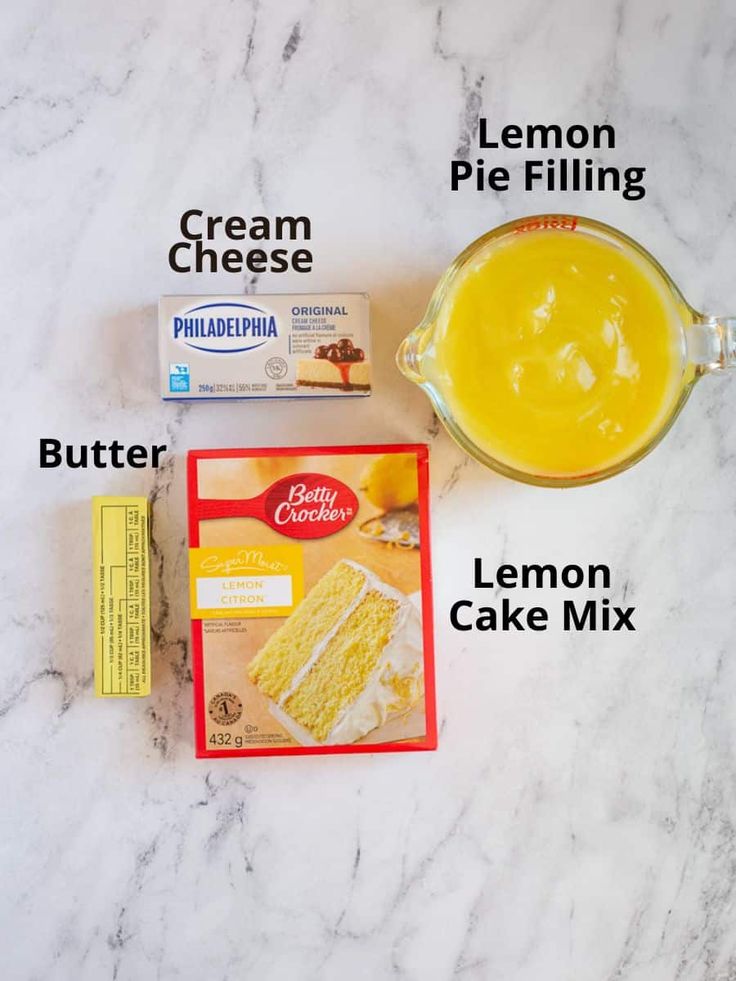 ingredients needed to make a cake mix on a marble counter top, including cream, pie filling and lemon cake mix