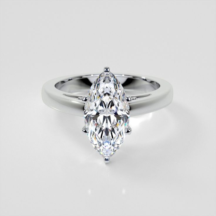 a white gold ring with a pear shaped diamond in the center, on a plain surface