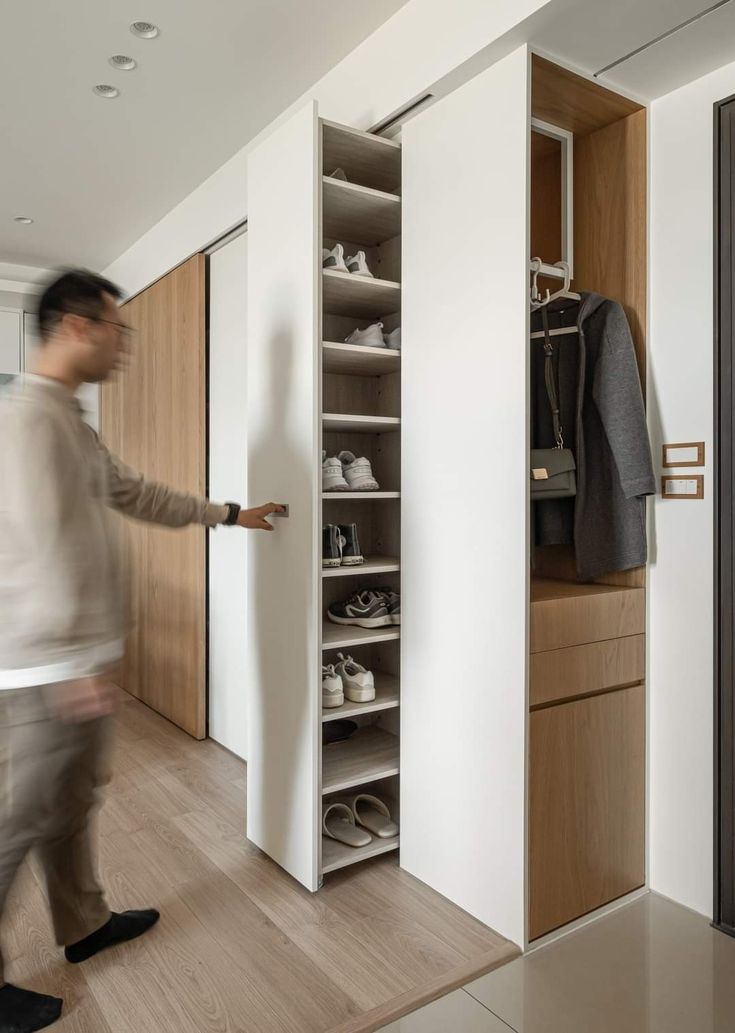 a man walking past a closet filled with shoes