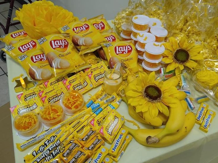 sunflowers and candy are displayed on a table with snacks, candies, and other items