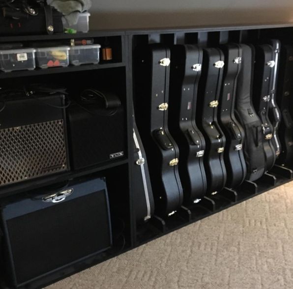 guitars are lined up against the wall in an office area with carpeted flooring