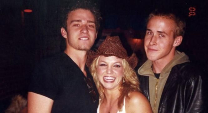 two men and a woman standing next to each other in front of a man wearing a cowboy hat