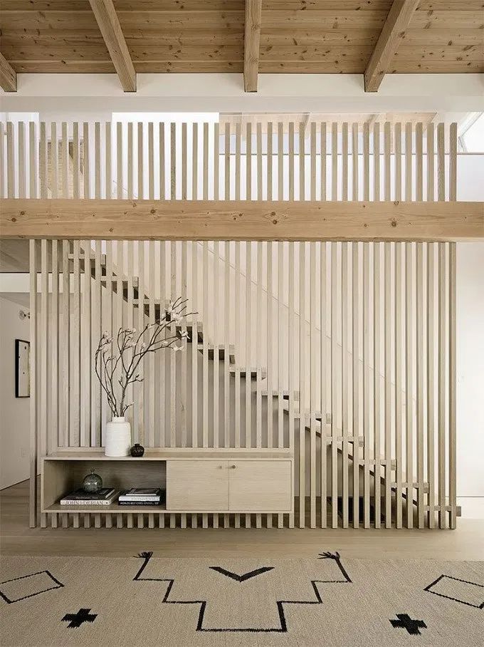 a living room filled with furniture and a stair case next to a wooden railing wall