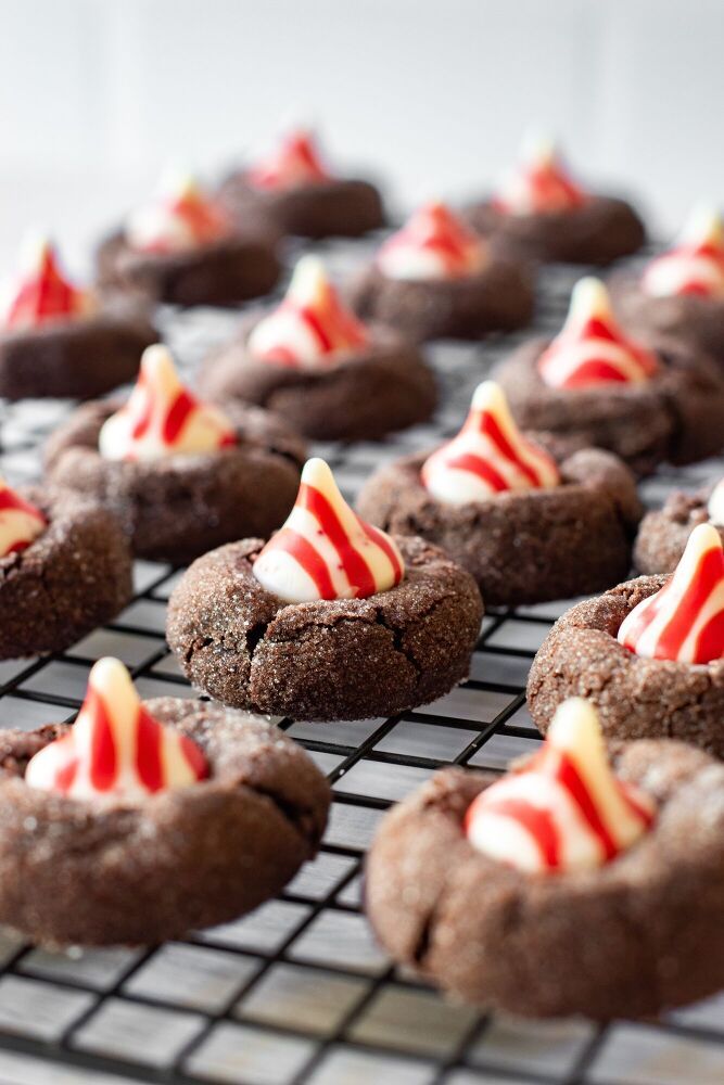 chocolate cookies with white and red icing on a cooling rack