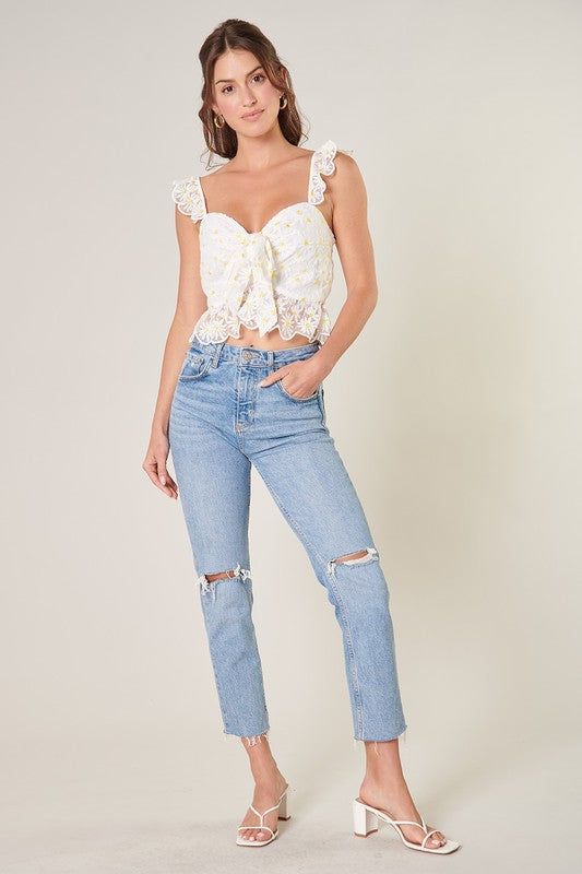 Feel the sun on your skin in this charming ruffled crop top. Embroidered daisies shape this cropped top, featuring ruffle straps that join a fitted bodice with a sweetheart neckline. It maintains a shapely fit with a peplum ruffle along the waistline. A tie front detail sits at the heart of the neckline to create a flirty flair. Wear it with your favorite high rise bottoms for a finished look.- Hook and eye closure- Tie front detail- Embroidered- Peplum- Color: White FloralSize + Fit - Model is Summer Lace Trim Cropped Crop Top, Lace Trim Cropped Top For Summer, Cropped Lace Trim Crop Top For Summer, Feminine Spring Crop Top With Ruffled Straps, Feminine Summer Crop Top With Ruffled Straps, Feminine Ruffled Straps Crop Top For Spring, Feminine Crop Top With Ruffled Straps, Summer Ruffled Straps Crop Top For Day Out, Lace Trim Cropped Top For Day Out