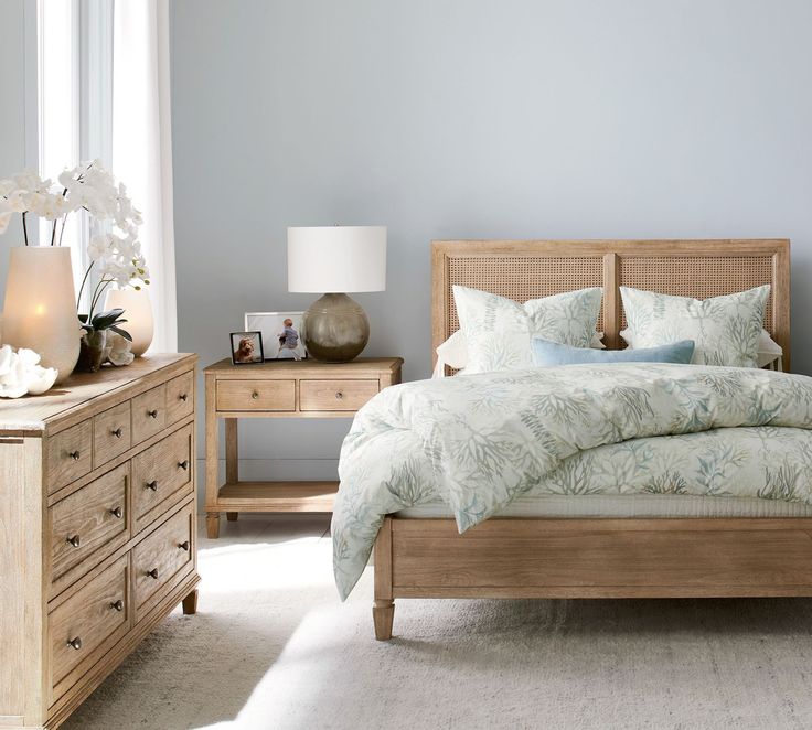 a bed sitting in a bedroom next to a dresser with drawers and lamps on top of it