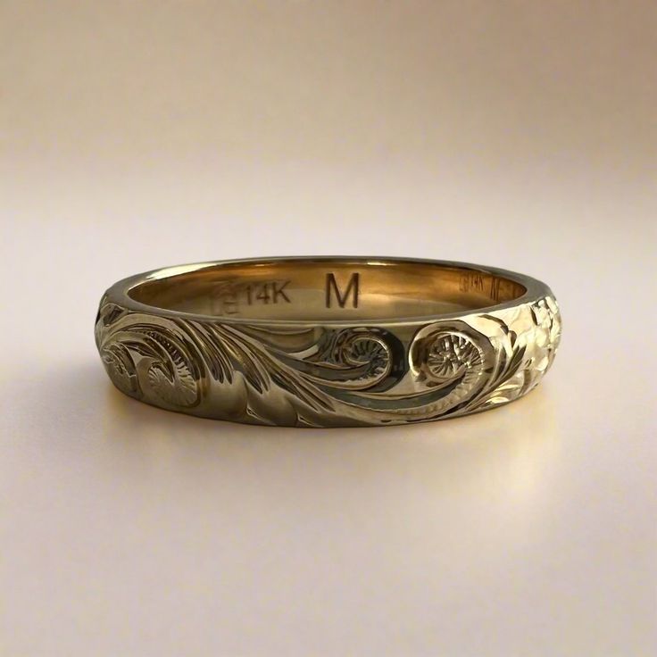 a gold wedding band with flowers and leaves on it, engraved in white gold or yellow gold