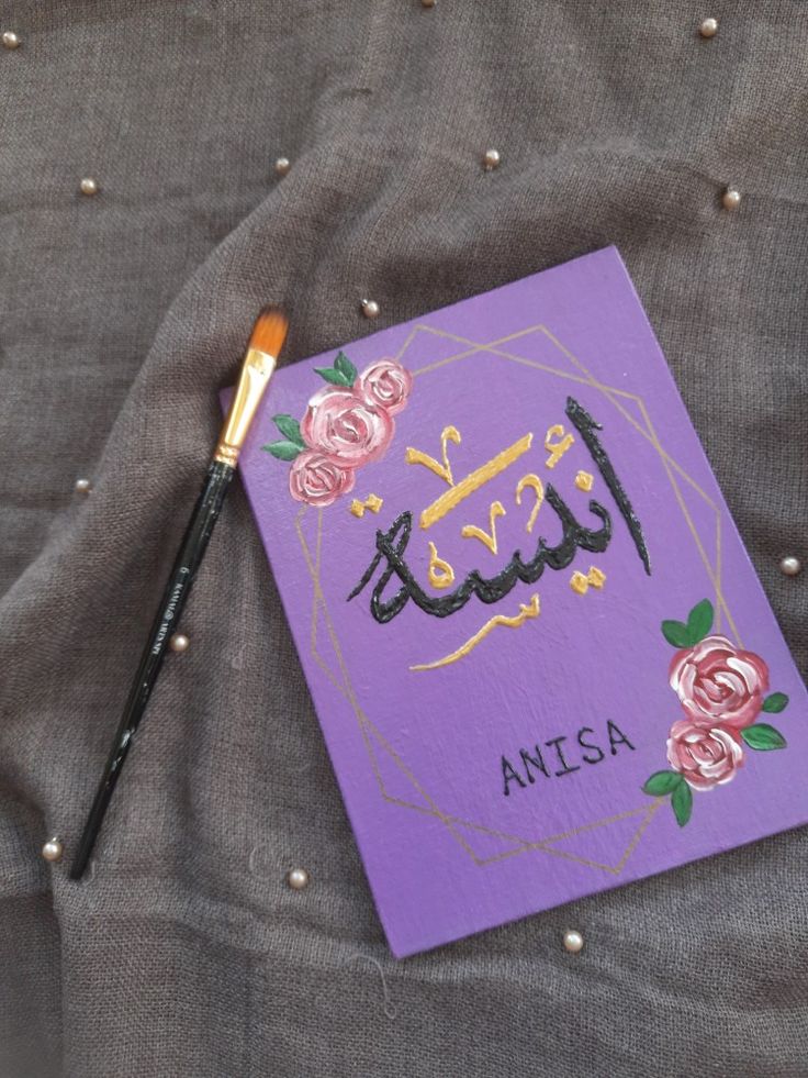 a purple book with arabic writing on it and a brush resting on the front cover