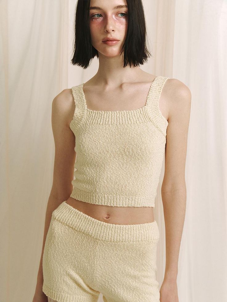 This product is a crop knit sleeveless top that offers a contemporary and cozy addition to any wardrobe with its textured fabric and cropped cut. The piece is designed for a snug fit that highlights the waist, making it an excellent partner to high-waisted bottoms. - The top features a delicate knit pattern that adds a touch of elegance to the simple silhouette.- Its cropped length is on-trend, perfect for pairing with various high-waisted garments.- The sleeveless design makes it ideal for layering under jackets or wearing alone in warmer weather.- Constructed with comfort in mind, the soft knit material provides a gentle feel against the skin. Fitted Cropped Beige Tank Top, Fitted Cropped Knit Sweater Vest, Cropped Knit Fitted Sweater Vest, Seamless Cropped Knit Tank Top, Chic Textured Knit Fitted Tank Top, Seamless Cropped Knit Crop Top, Chic Fitted Textured Knit Tank Top, Fitted Cropped Knit Tank Top, Fitted Knit Tank Crop Top