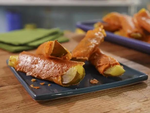 two plates with food on them sitting on a wooden table next to green napkins