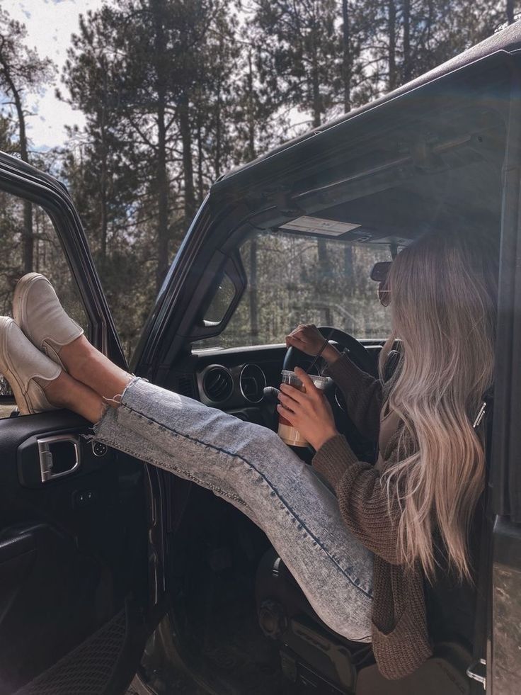 a woman sitting in the drivers seat of a pickup truck with her feet on the steering wheel