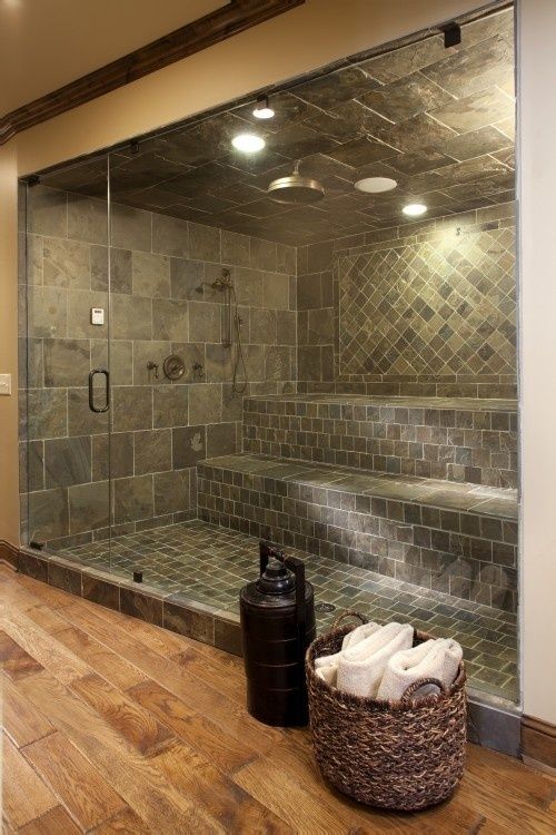 a walk in shower sitting inside of a bathroom next to a trash can and basket