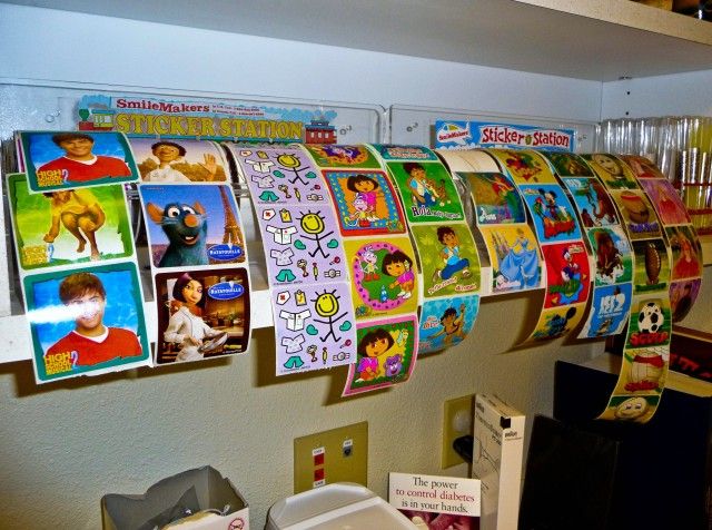 many children's pictures are hanging on the wall in an office area with other items