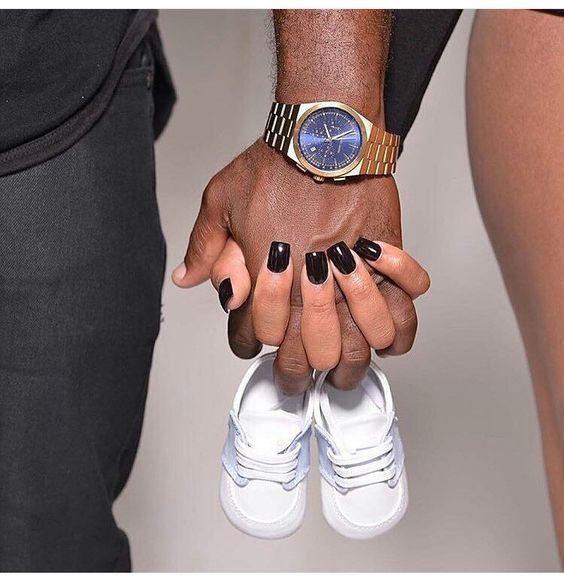 two people holding hands with black and white manies on their fingers, one wearing a watch