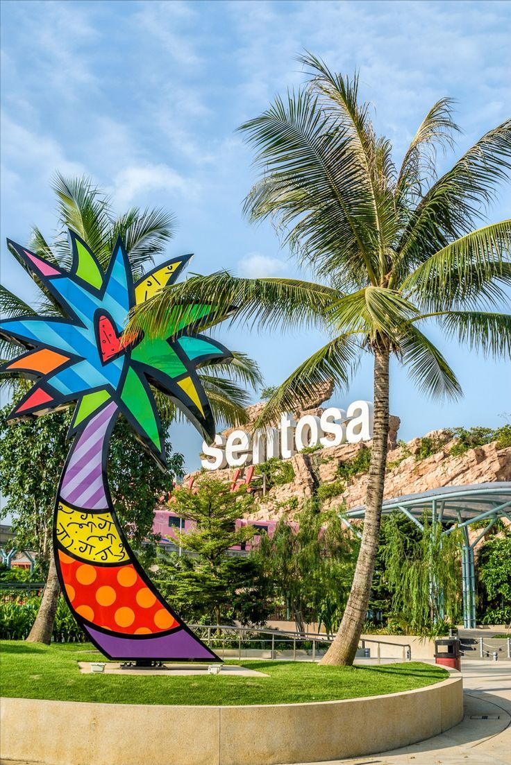 there is a large colorful palm tree in front of the sign that says sentosa