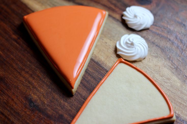 two pieces of cake sitting on top of a wooden table next to white frosting