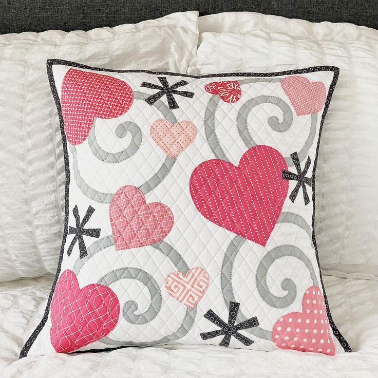 a pillow with hearts on it sitting on a bed