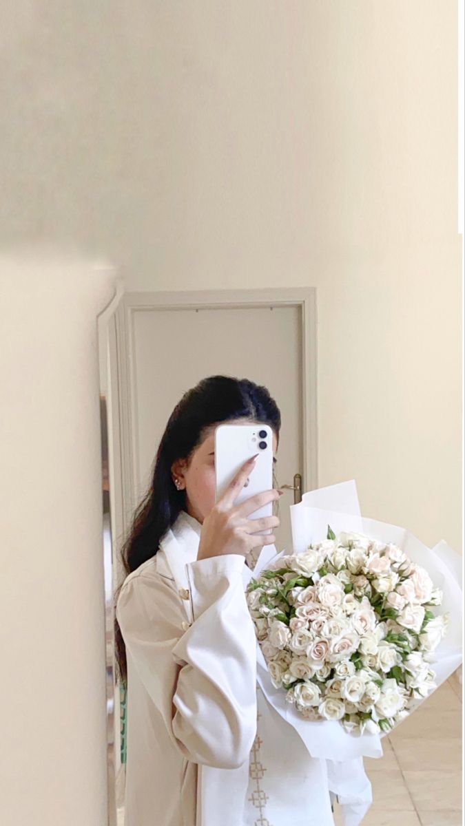 a woman taking a selfie while holding a bouquet of flowers