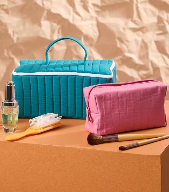 two cosmetic bags sitting on top of a table next to a brush and toothbrush