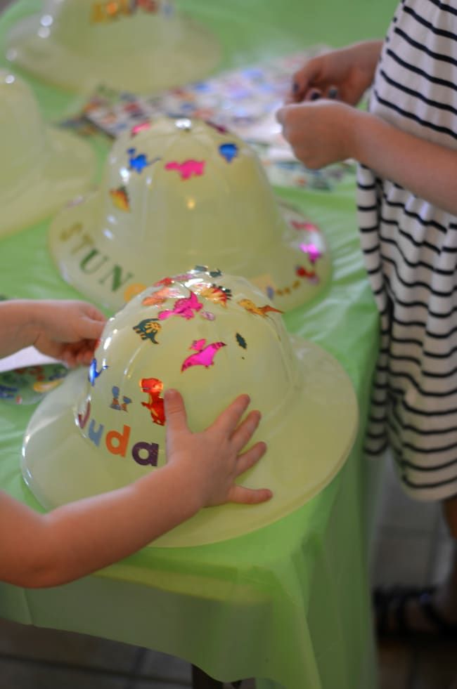 two children are sitting at a table with hats on it and one child is reaching for the hat