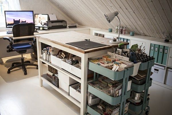 an attic office with two desks and several storage bins on the bottom shelf