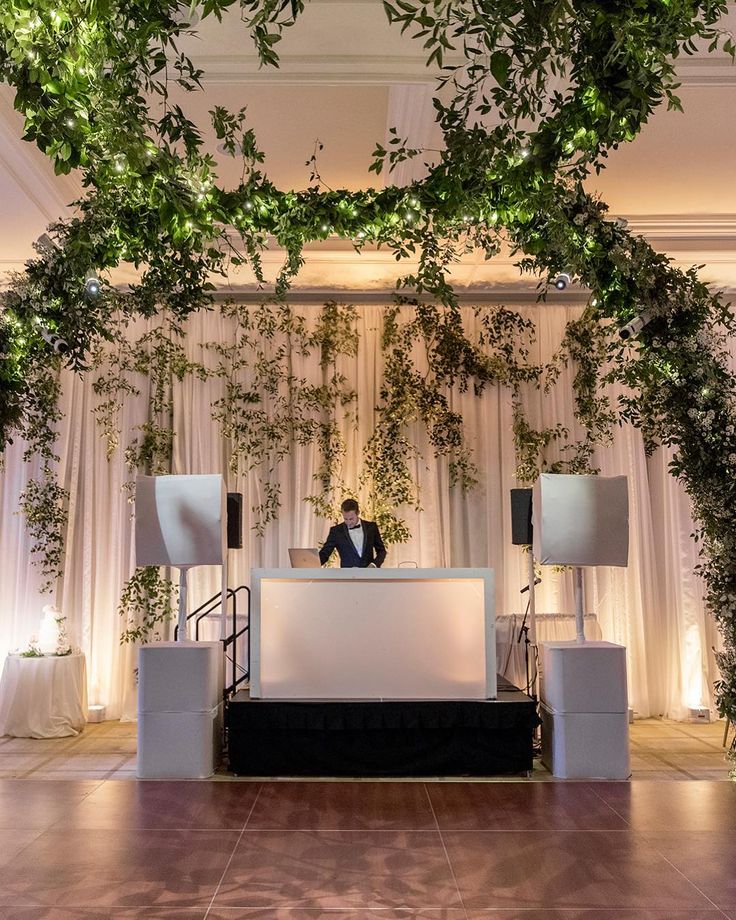 a person sitting at a reception table with greenery on the wall