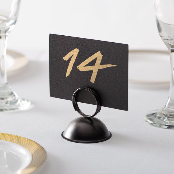 a black table number sitting on top of a white table with gold trimmings