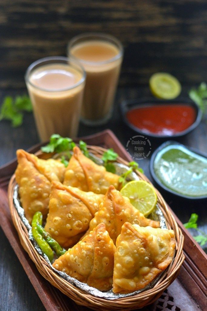 some food is sitting in a basket on a table with two cups and sauces