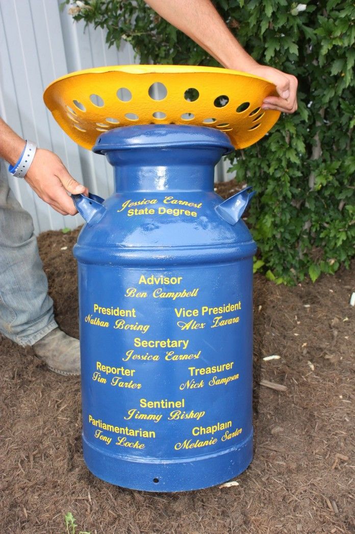 a man is pouring water into a large blue pot with holes on the top and bottom