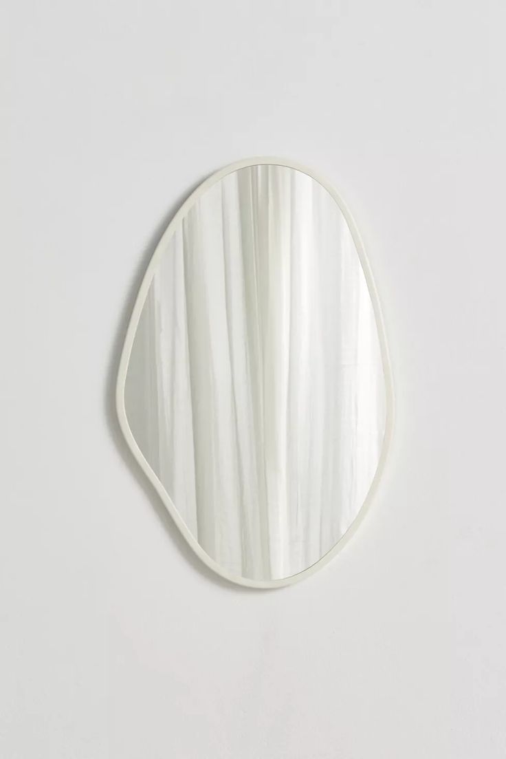 an oval mirror with white stripes on the bottom and one reflection in the middle, against a white wall