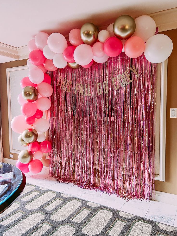 balloons and streamers decorate the entrance to a pink, gold and white birthday party