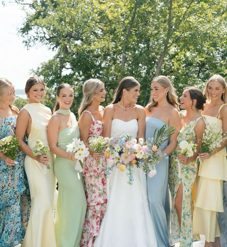 a group of women standing next to each other wearing dresses and holding bouquets in their hands