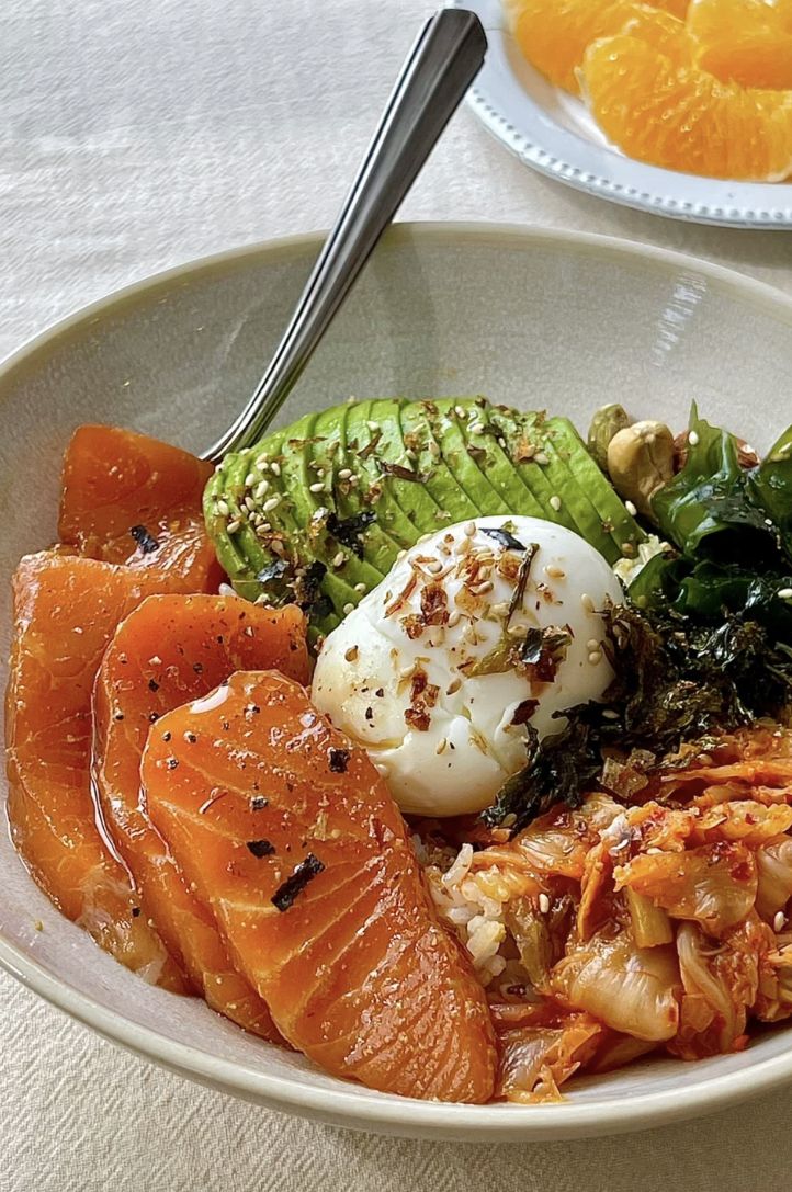 a white bowl filled with different types of food next to oranges and broccoli