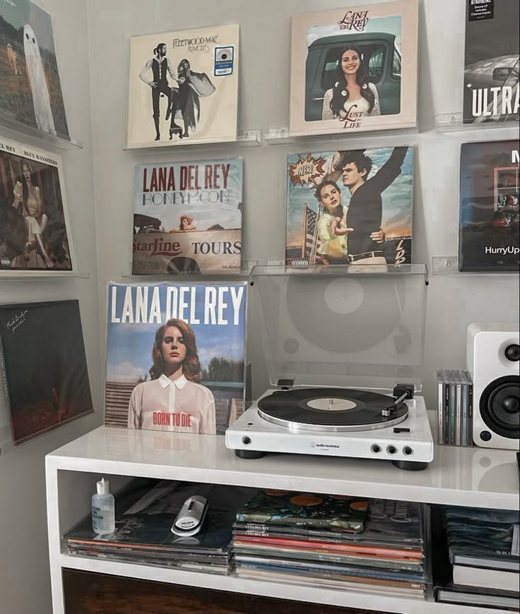 a record player sitting on top of a white shelf in front of a wall full of movies