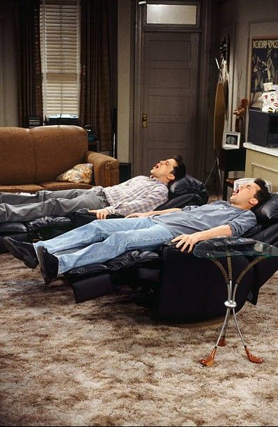 two men laying on recliners in a living room