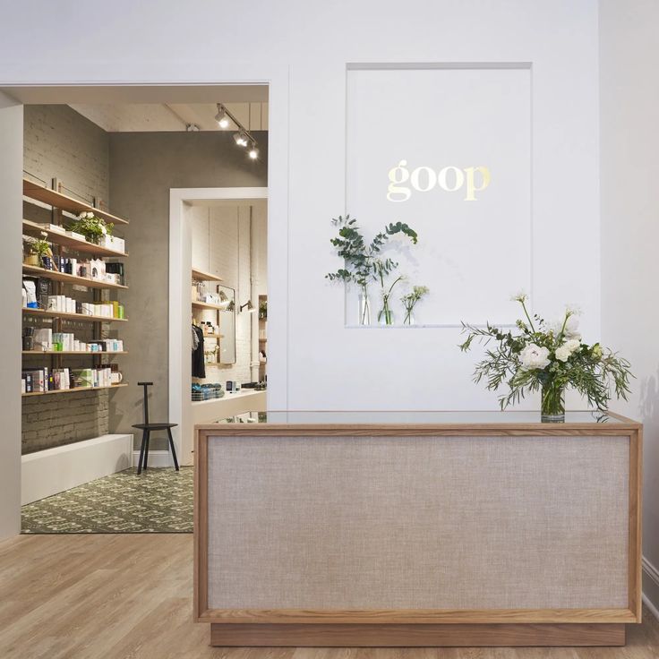 the front desk of a hair salon with plants in vases on it's counter